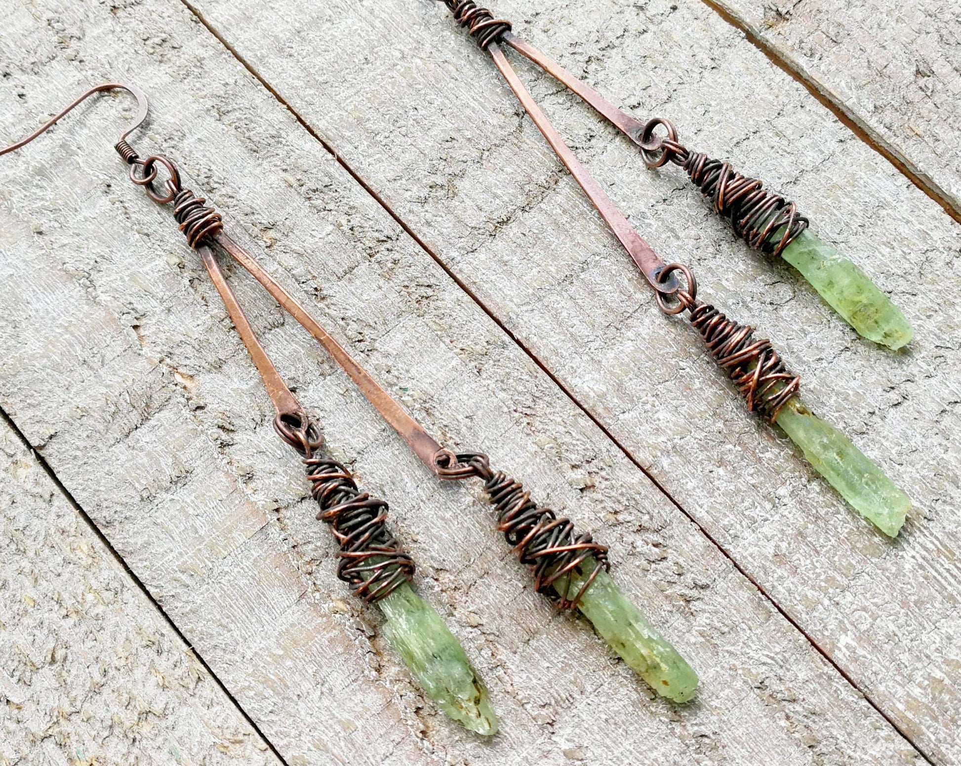 A top view of Boho Green Kyanite Earrings on a wooden background.