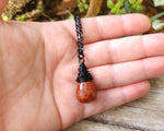Fire agate necklace on a black chain, held in hand to show scale.