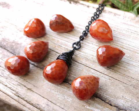 Fire agate necklace on a black chain on wood background.