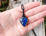 Guitar Pick Shaped Blue Labradorite Pendant held in hand to show scale.