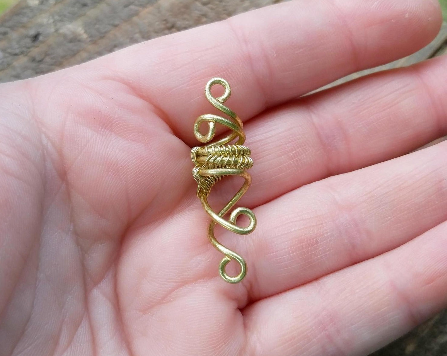 A top view of a Small Woven Brass Dread Bead in hand.