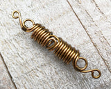 Close up view of a Filigree Boho Dread Bead on a wooden background.