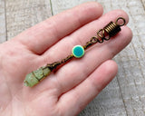 A top view of a Green Kyanite Squiggle Loc Bead in hand. 