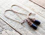 A pair of Black Onyx Earrings on a wooden background.