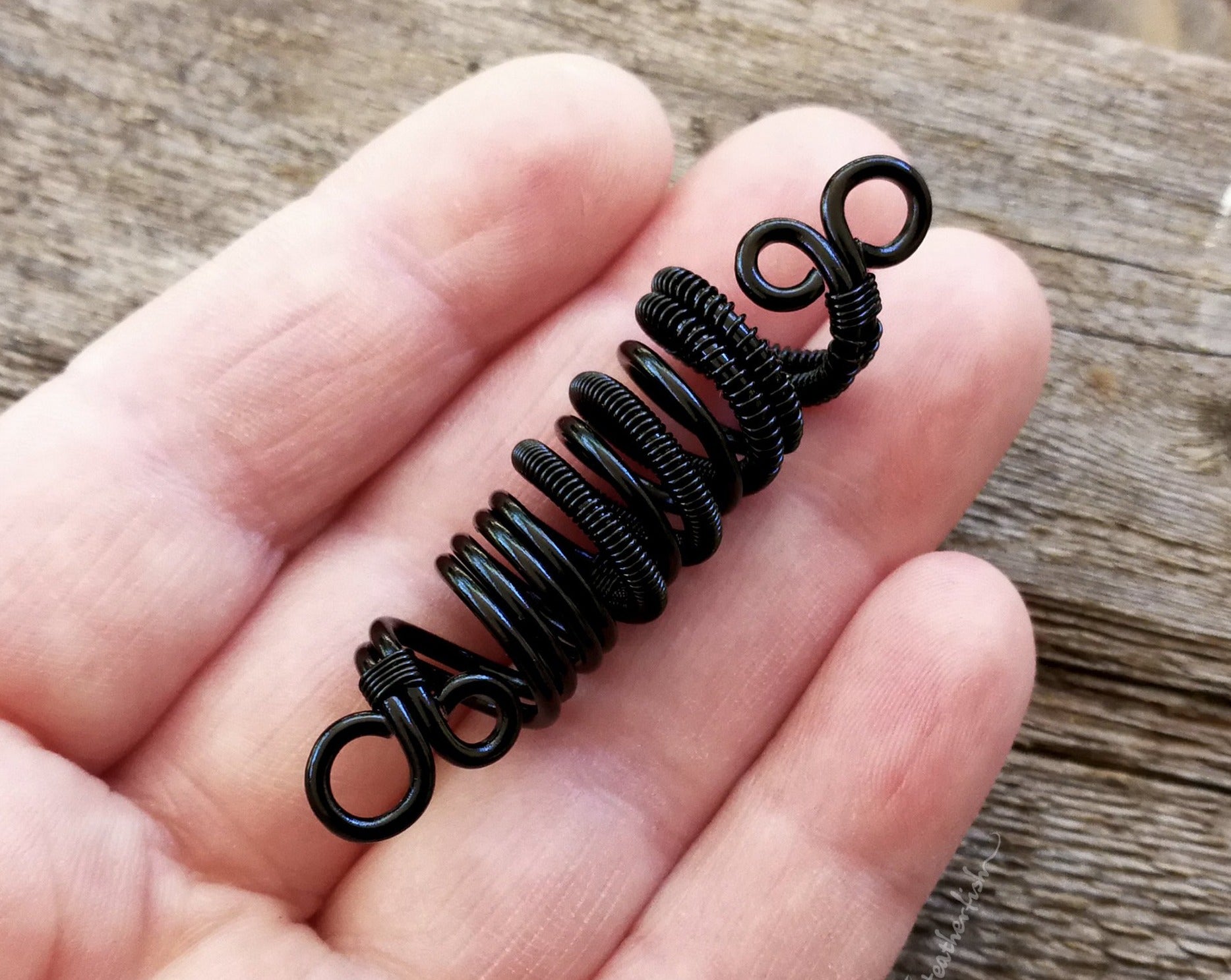 A Black Woven Dread Bead in hand.