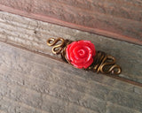 A top view of a Red Rose Dread Bead on a wooden background.