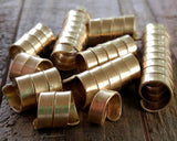 A set of 10 Brass Dread Beads in varies of length on a wooden background.