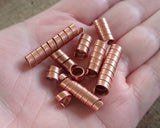 A top view of Copper Dread Beads Set of 10 Varied Length in hand.