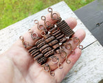 A top view of One Copper Dread Bead in different styles in hand.