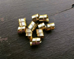A top view of Stylized Brass Dread Beads Set of 10.