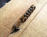 A side view of a Shark Tooth Dread Bead with Hematite Accents.