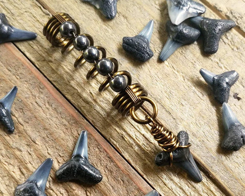 A close up view of a Shark Tooth Dread Bead with Hematite Accents.