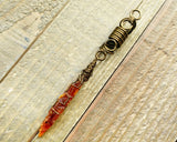 A top view of Orange Kyanite Dread Bead on a wooden background.