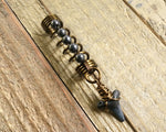 A top view of a Shark Tooth Dread Bead with Hematite Accents.