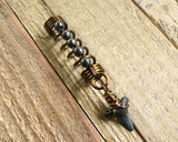 A top view of a Shark Tooth Dread Bead with Hematite Accents.