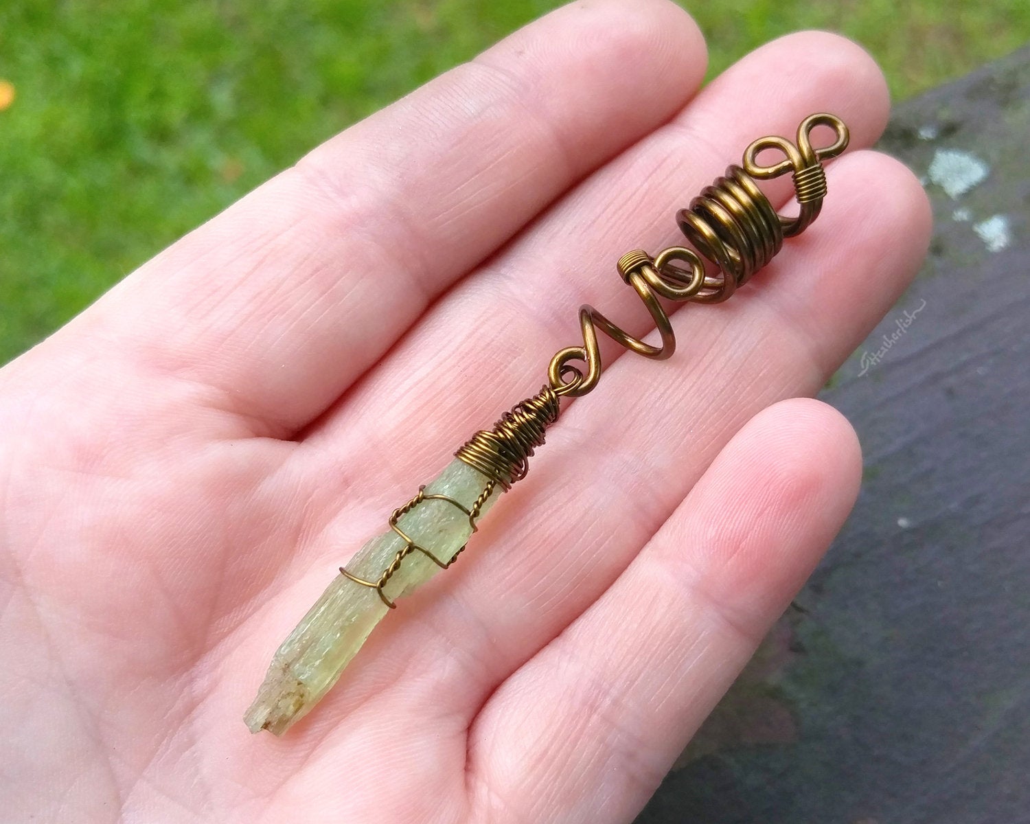 A top view of a Green Kyanite Dread Bead in hand. 