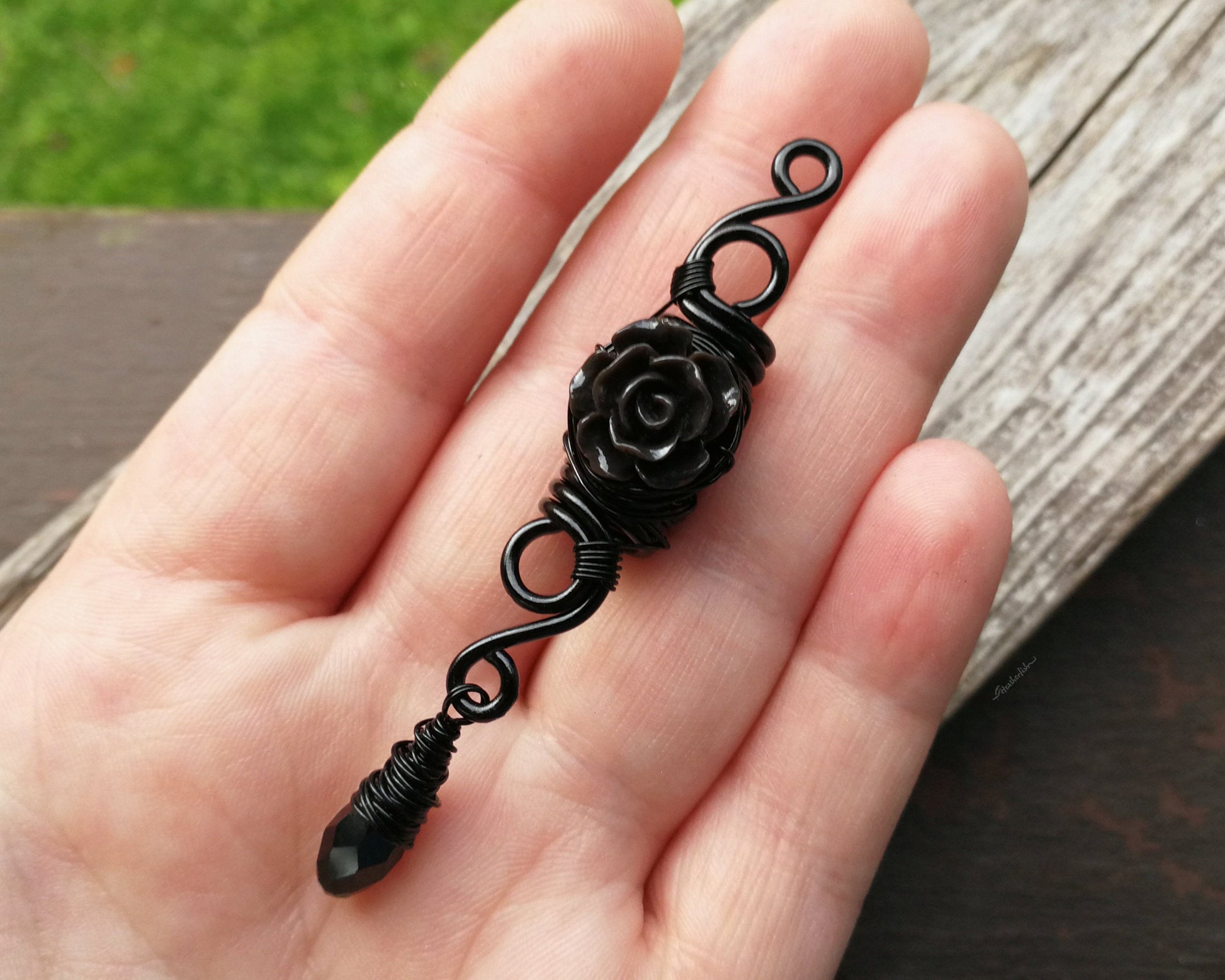 A top view of a Goth Dreadlock jewelry Black Rose in hand.