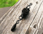A close up of a Goth Dreadlock jewelry Black Rose on a wooden background.