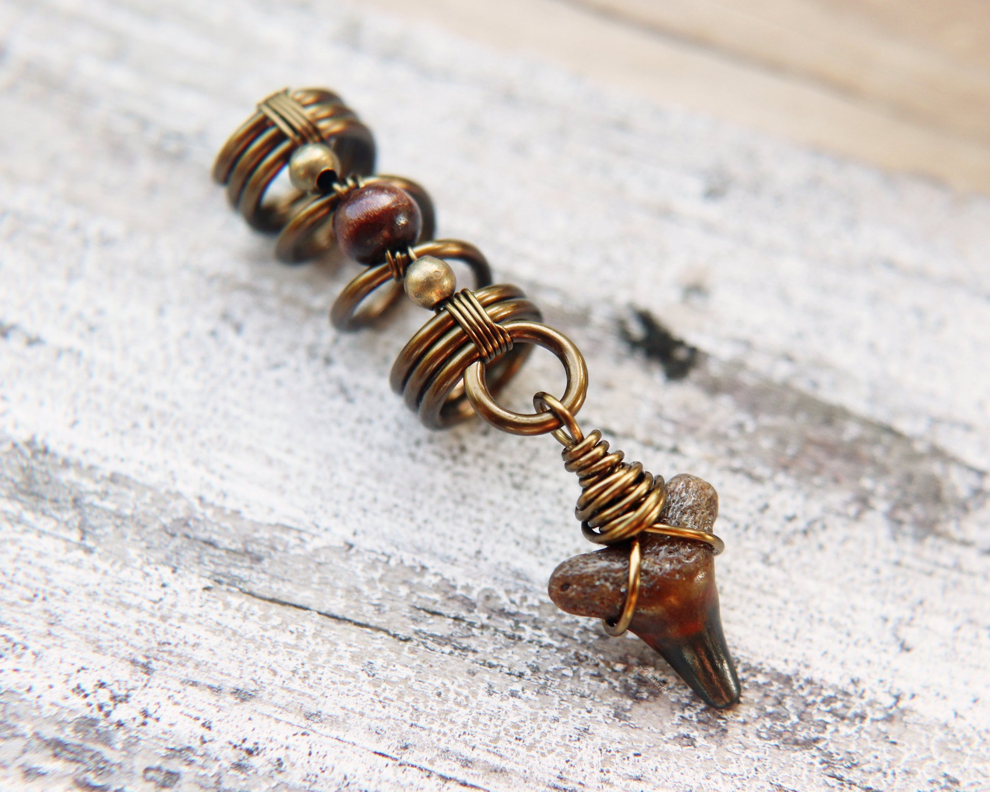 A side view of a Shark Tooth Dread Bead with Wood Accents.