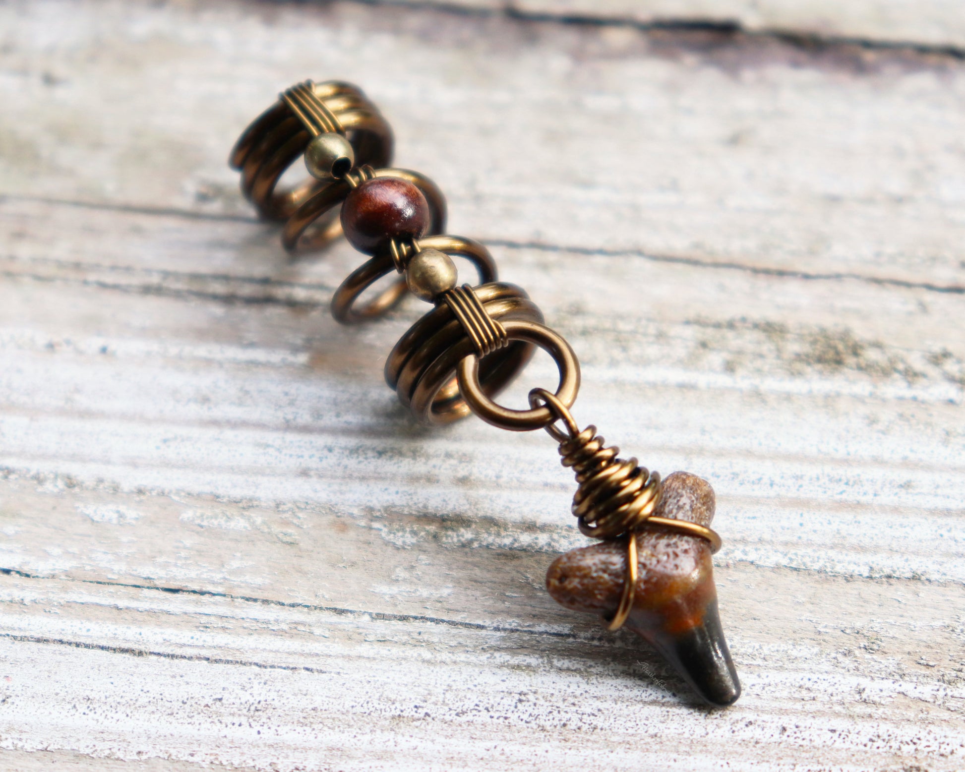 A top view of a Shark Tooth Dread Bead with Wood Accents.