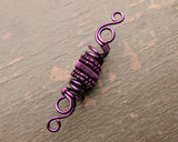 A top view of a Purple Woven Dread Bead on a wood background.