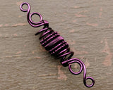 A close up view of a Purple Woven Dread Bead.