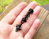 A top view of a Shark Tooth Dread Bead with Black Lava Beads in hand.