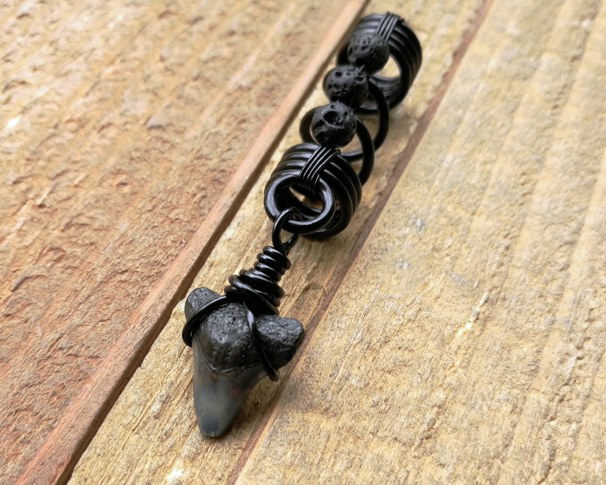 A side view of a Shark Tooth Dread Bead with Black Lava Beads.