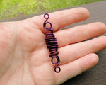A top view of a Purple Woven Dread Bead in hand.