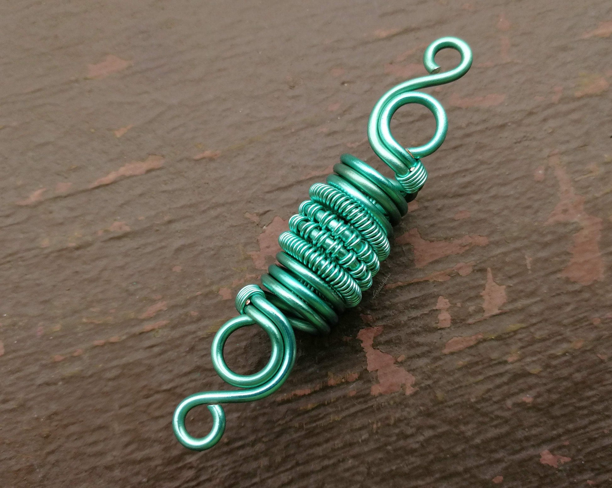 A top view of a Woven Aqua Dread Bead.