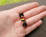 A top view of a Striped Rasta Dread Bead in hand.