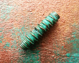 A side view of a Green Patina Copper Dread Bead. 