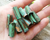 A top view of Green Patina Copper Tube Beads in hand. 