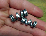 Photo of two hammered aluminum dread bead coils in hand