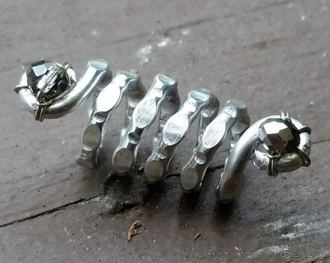 A close up view of a Textured Aluminum Dreadlock Bead.